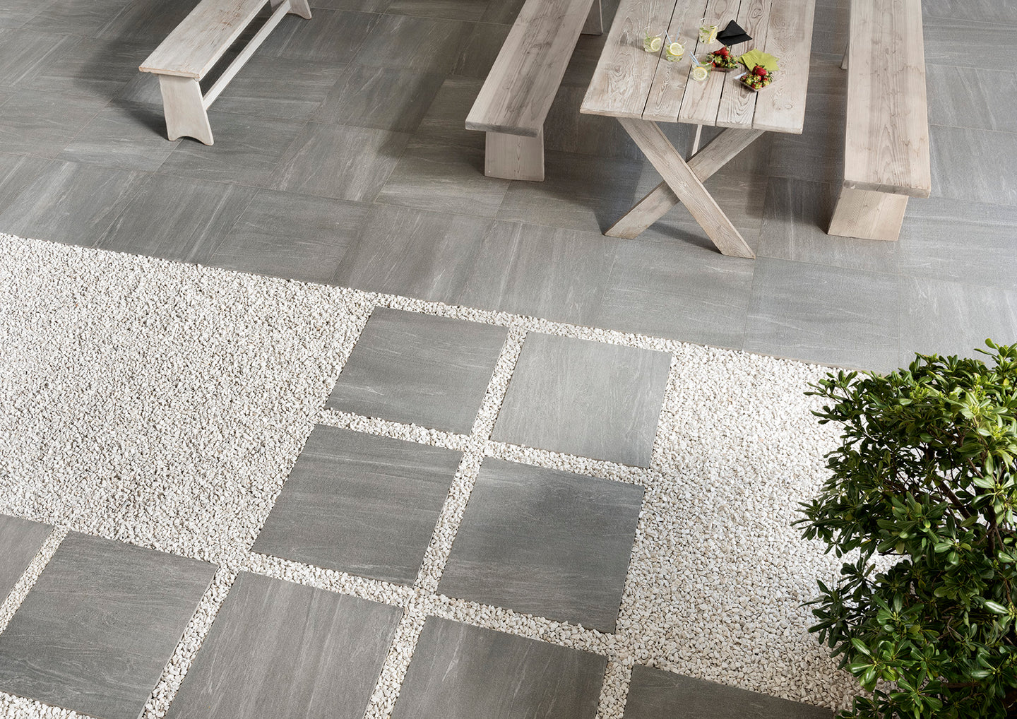 24x24 Grey pavers over white gravel with a natural wood pick nick table.